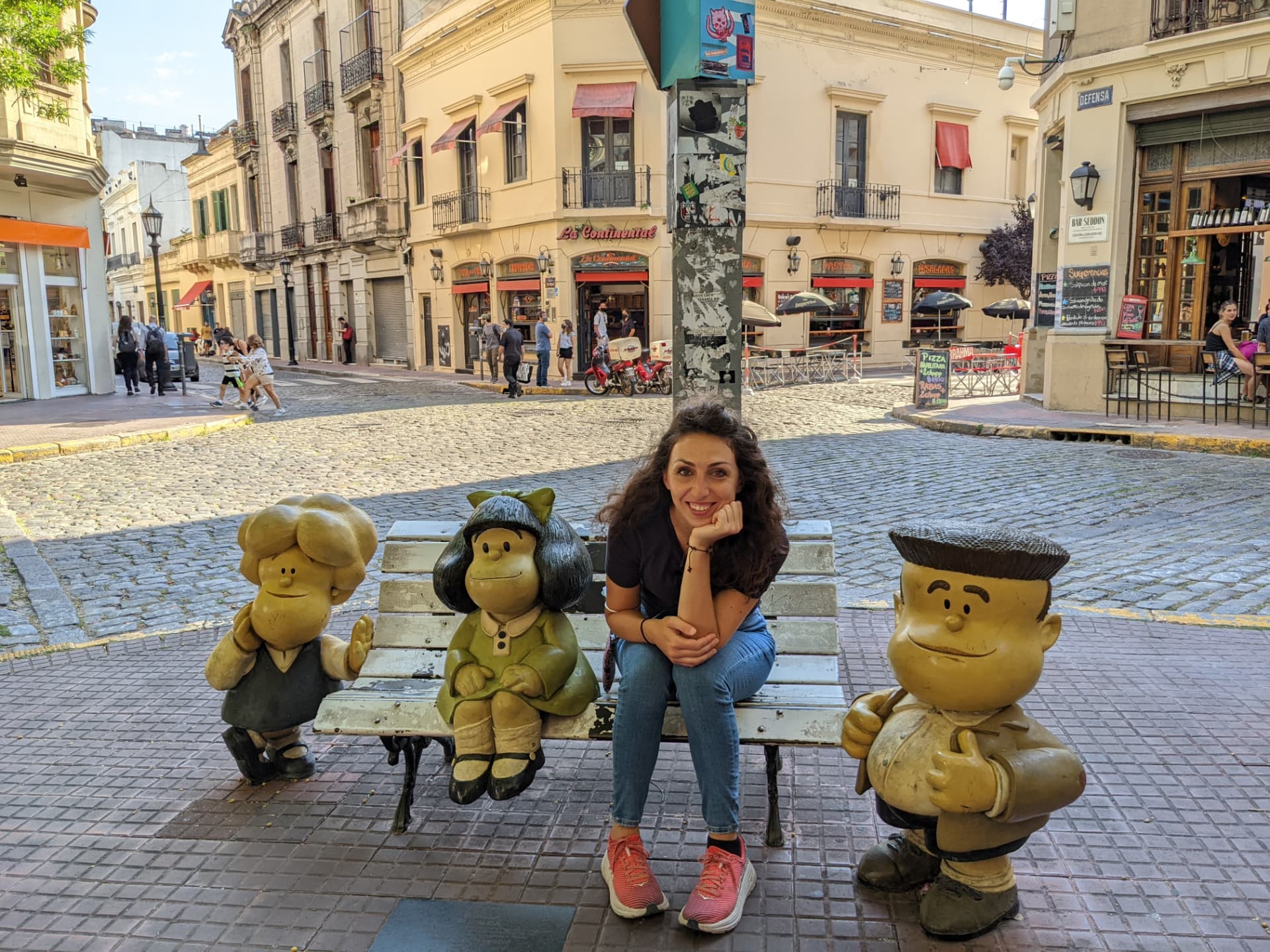 Marta sitting on a bench beside the Mafalda statues in San Telmo, Buenos Aires